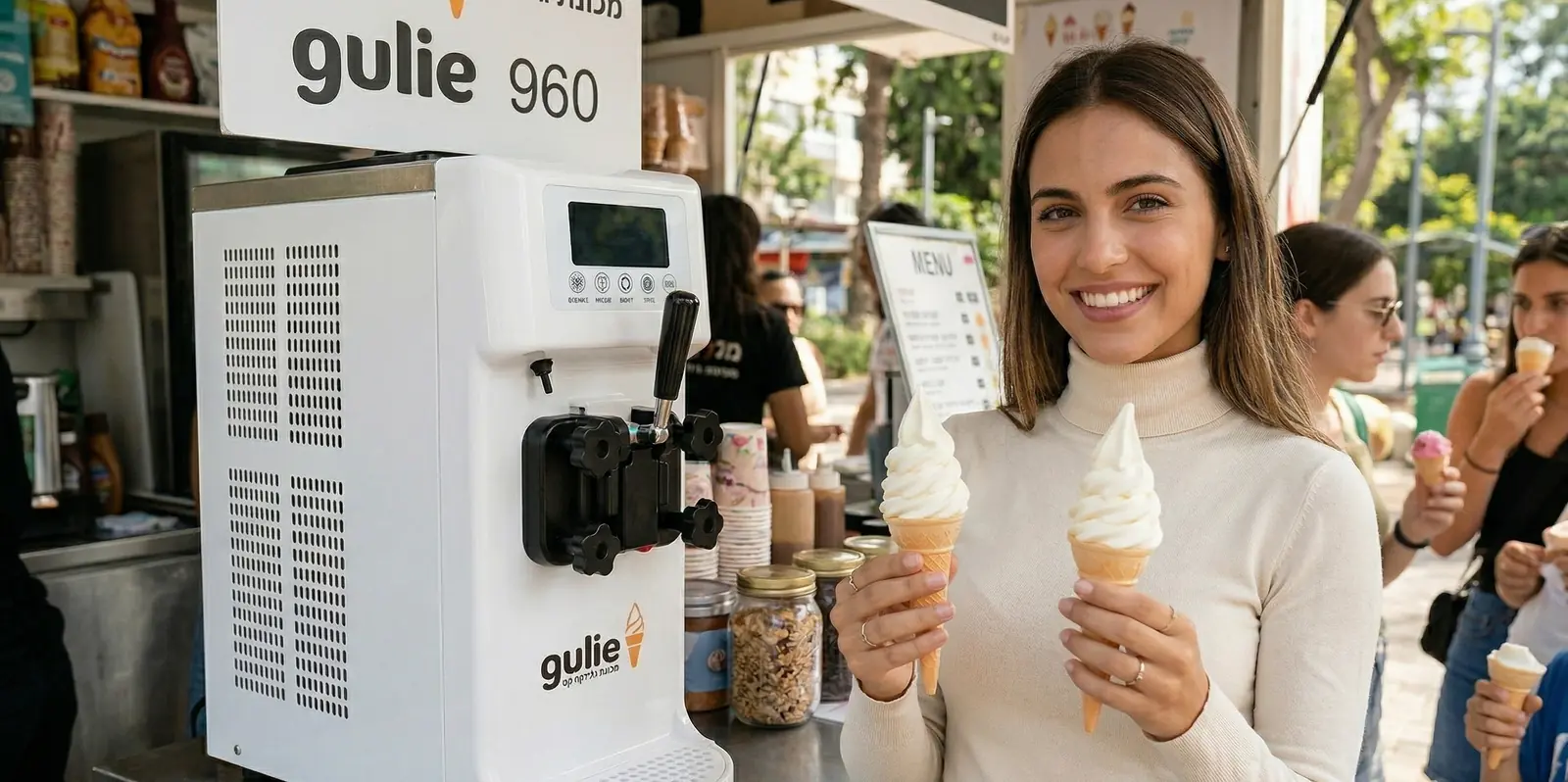מכונת גלידה GULIE 960 בדוכן פעיל, לקוחה מחזיקה שתי גלידות רכות